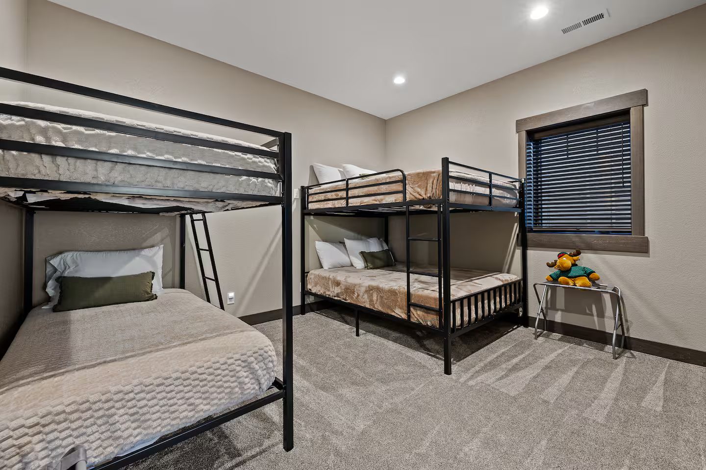 Bunk room with two sets of black metal bunk beds and carpet