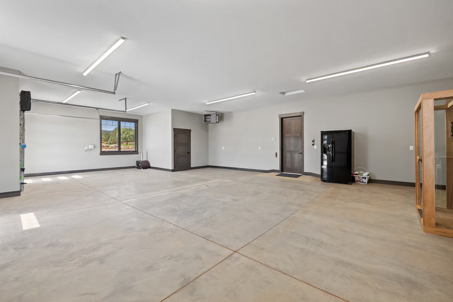 Large garage with smooth concrete floors, a second refrigerator and the infrared sauna, with room for motorcycles, side-by-sides and large vehicles