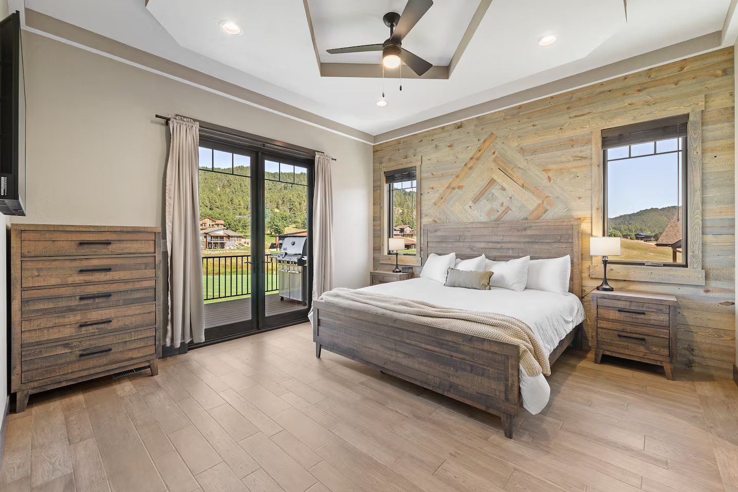 Primary bedroom with a king bed, a wood plank accent wall, and French doors to a deck overlooking the course